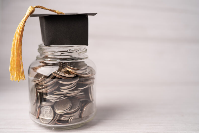 Graduation gap hat on coins money in jar for education fund